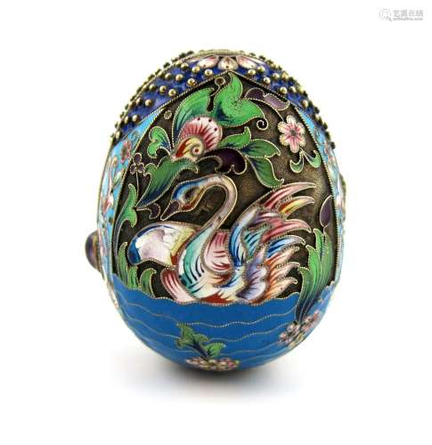 A Russian silver-gilt and enamel egg, decorated with swans on a lake with foliate scroll decoration,