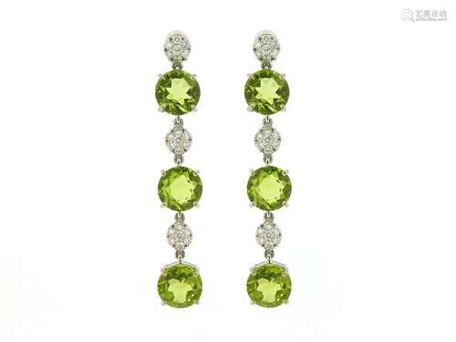 A pair of peridot and diamond drop earrings, each earring set with three circular-cut peridots and