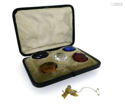 A cased glass specimen stone set, with a purple, blue, red (damaged), yellow and colourless oval-