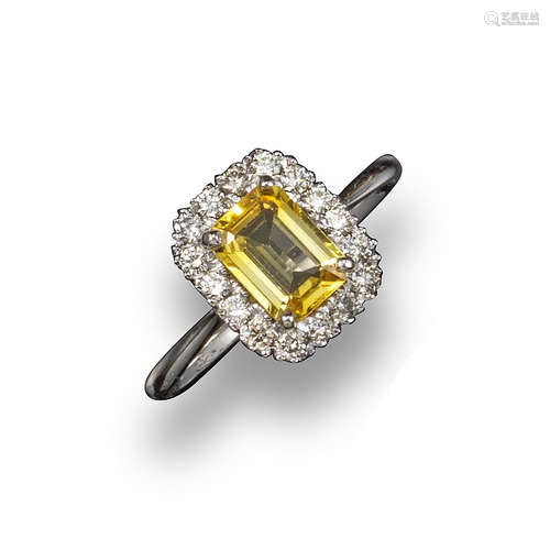 An emerald-cut yellow sapphire and diamond cluster ring, the sapphire set within a surround of round