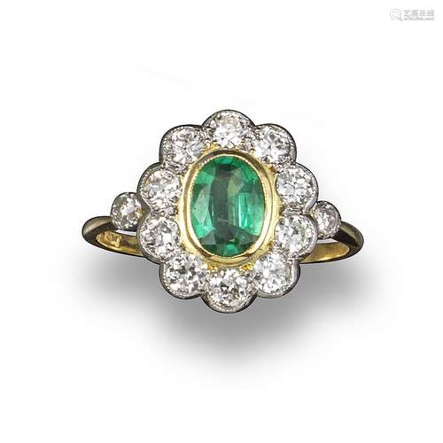 An emerald and diamond cluster ring, the oval-shaped emerald set within a surround of old circular-