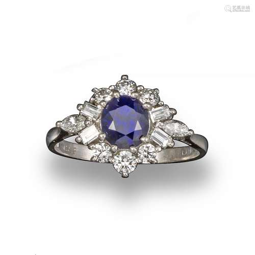 A sapphire and diamond cluster ring, the slightly oval-shaped sapphire set within a surround of