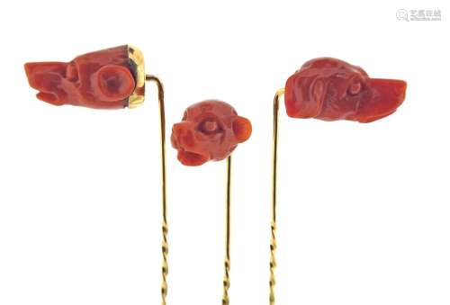 Three carved coral stick pins, realistically depicting dog's heads in coral, set in yellow gold