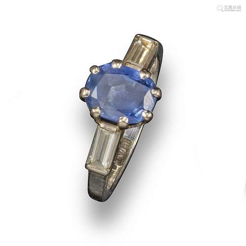 A sapphire and diamond ring, the oval-shaped sapphire is flanked by baguette-shaped diamonds in