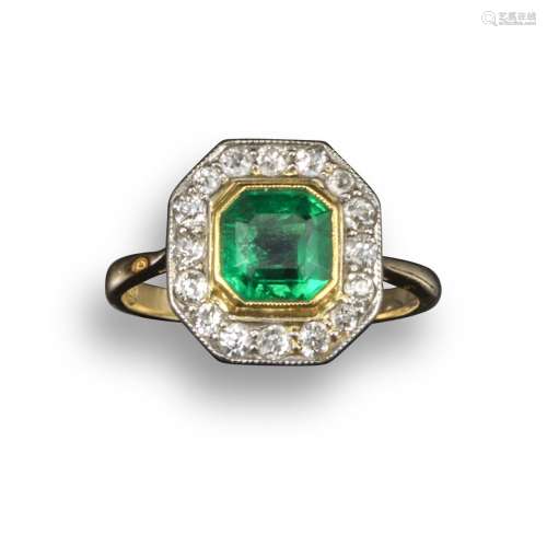 An emerald and diamond cluster ring, the octagonal-shaped emerald set within a surround of old