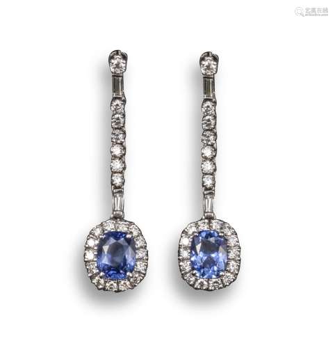 A pair of sapphire and diamond drop earrings, the oval-shaped sapphires are set within a surround of