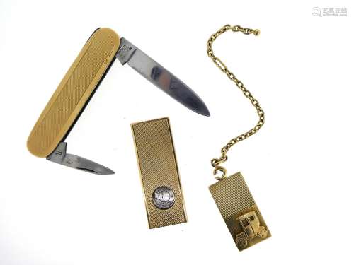 A gold penknife, with engine turned decoration, a gold cigar cutter and a gold charm depicting a car