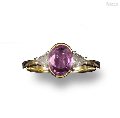 A pink sapphire and diamond ring, the oval-shaped sapphire set with two triangular shoulder diamonds