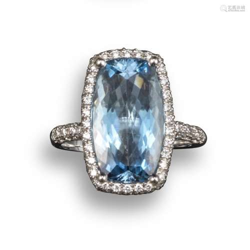 An aquamarine and diamond cluster ring, the rectangular cushion-shaped aquamarine is set within a