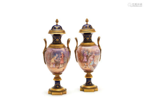 in the Louis XVI style A pair of early 20th century French gilt bronze mounted Sevres style gilt tooled cobalt blue ground porcelain garniture vases and covers