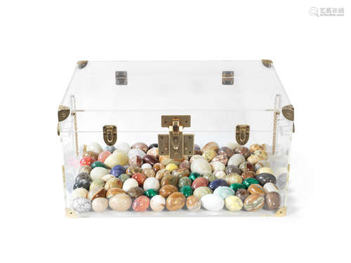 A collection of polished hardstone and mineral eggs contained in a brass mounted perspex trunk