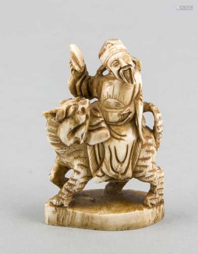 Small ivory carving, China, around 1900, riding man on cat, H. 8 cm