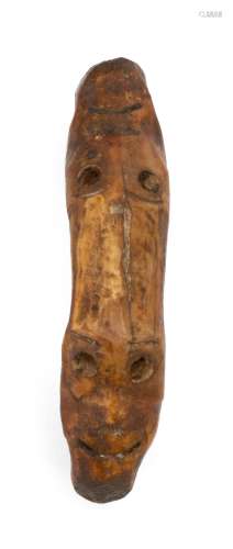 ESKIMO CARVED PETRIFIED WALRUS IVORY AMULET In an elongated form with two rings at ends and two faces carved into top. Length 3.75