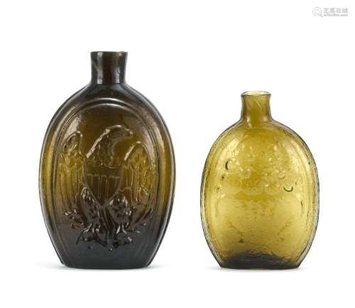TWO HISTORICAL BLOWN-MOLDED GLASS FLASKS Both in amber. One with molded eagle and Liberty shield decoration. One with molded compote...