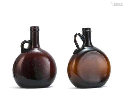 TWO BLOWN-MOLDED GLASS BOTTLES Both in amber. Both with applied handles. Heights 7.5