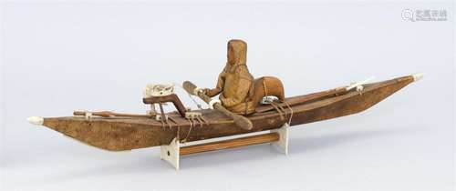 MODEL OF AN ESKIMO KAYAK Kayak with sealskin-covered frame. Figure and paddle carved from cedar. Carved seal bone details including...