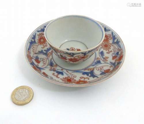 A Japanese Imari cup and saucer, decorated in blue foliate designs with red