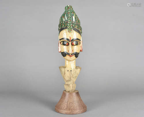 An Indian wooden carved figurine, of a gentleman with ornate moustache, large eyes and green head