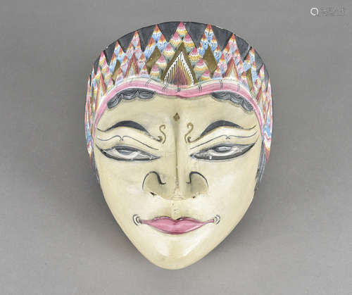 A South East Asian carved tribal mask, of a female head, the polychrome painted decoration with