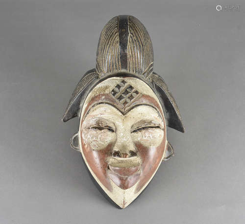 A carved African Punu mask, of a female head with stylised hair and polychrome decoration to face,