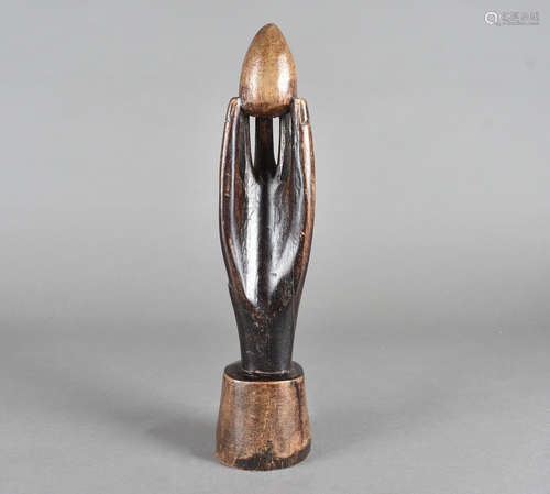 A carved hand holding an egg, possibly Pitcairn Island on a tapering circular base, 32 cm high