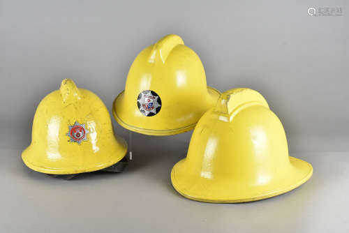 A 1970s Hampshire Fire and Rescue Service yellow fire helmet, together with a 1980s example, a 1990s