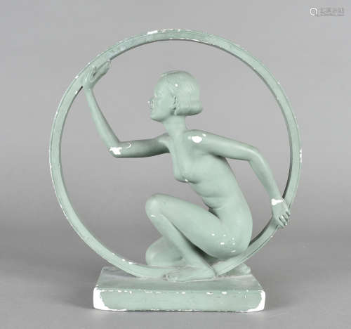 An Art Deco plaster figure, modelled as a kneeling nude female within a ring painted in green, 30 cm
