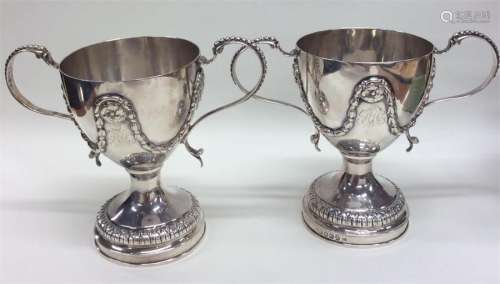 A pair of unusual silver loving cups decorated wit