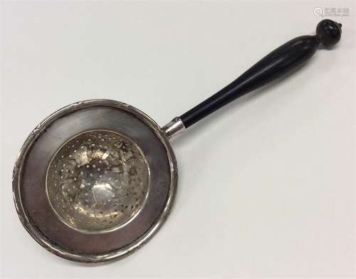 A Continental silver tea strainer with turned ebony handl