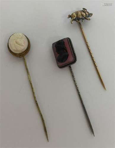 Two gold cameo stick pins together with one other.