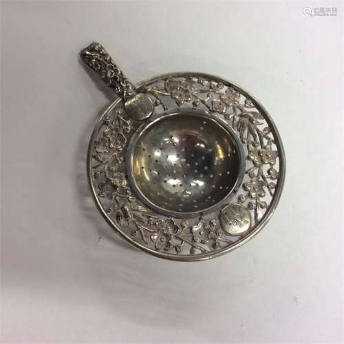 A small Chinese silver tea strainer decorated with