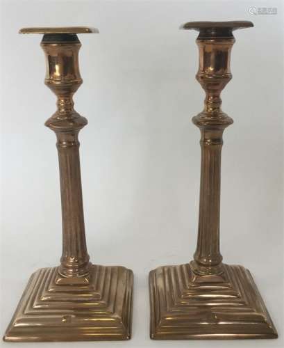 A pair of unusual brass candlesticks on step bases