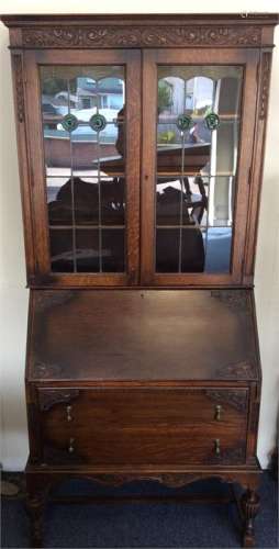 An oak carved bureau-bookcase with stretched base.