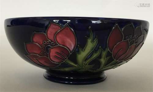 MOORCROFT: A blue-ground shallow bowl decorated wi