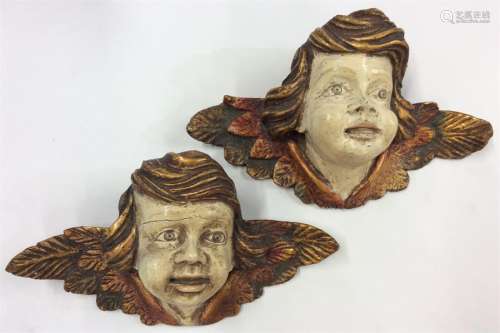 A pair of gilded wall plaques of winged infants wi
