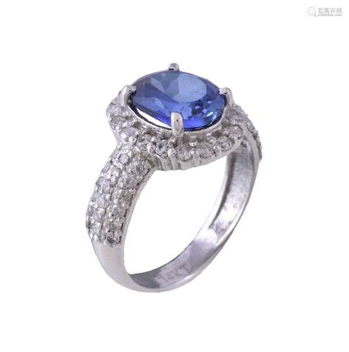 A tanzanite and diamond ring, the central oval cut tanzanite claw set within a surround of brilliant