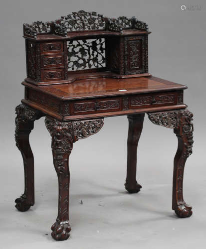 A Chinese carved hardwood writing desk, late Qing dynasty, the gallery back with carved and