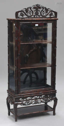 A Chinese hardwood display cabinet, late 19th/early 20th century, with glazed door and sides and