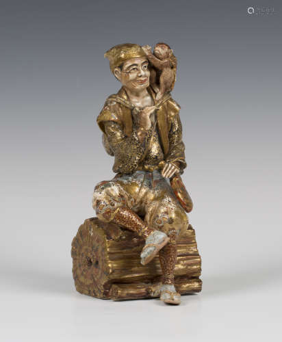 A Japanese Satsuma earthenware figure of a monkey trainer, Meiji period, modelled seated on a cut