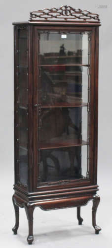 A Chinese hardwood display cabinet, early 20th century, the surmount pierced with stylized scrolls