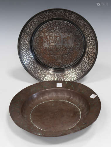 An Islamic silver inlaid copper circular dish, probably 19th century, decorated with a line of