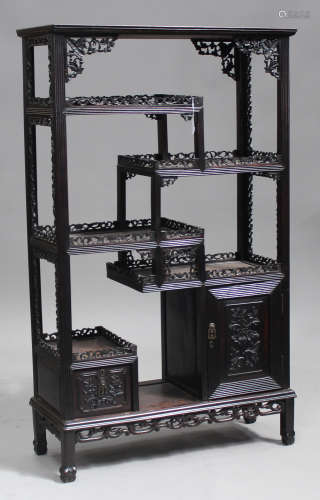 A Chinese hardwood display cabinet, early 20th century, the moulded pediment above an arrangement of