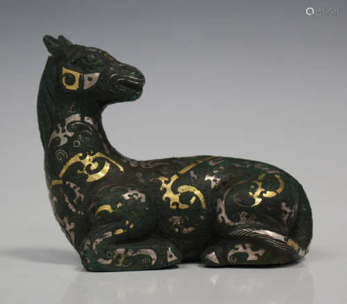 A Chinese inlaid cast bronze figure of a recumbent horse, Han style but later, modelled in a