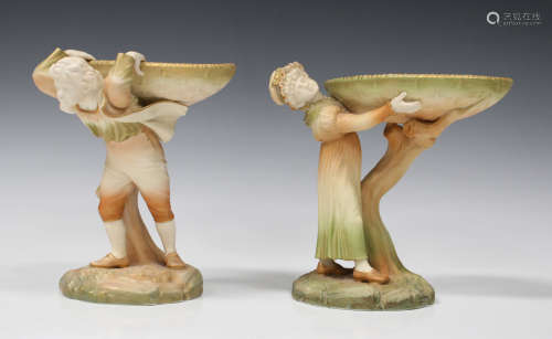 A pair of Royal Worcester blush ivory porcelain Rustic Boy and Girl table centrepieces, circa 1901