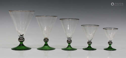 An Art Deco part suite of glasses of conical shape with silver lustre rims, raised on knopped