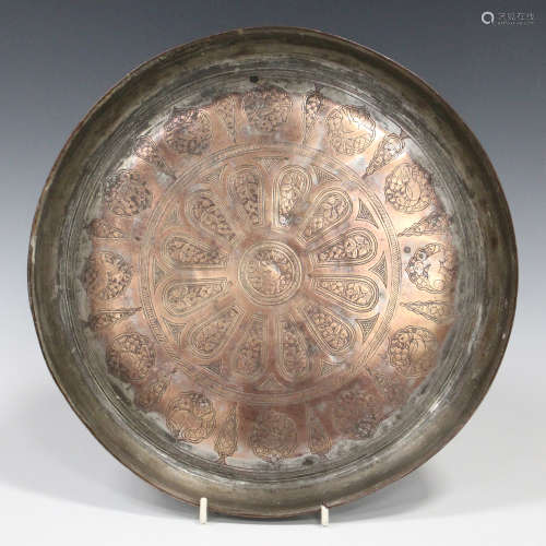 An Islamic copper circular dish, the centre engraved with panels of foliage and animals, diameter