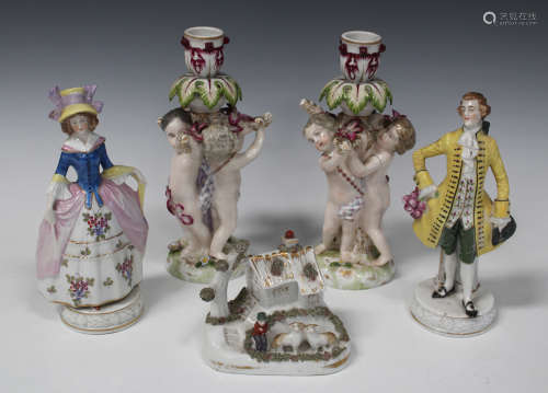 A pair of Continental porcelain figural candlesticks, late 19th century, both modelled as three