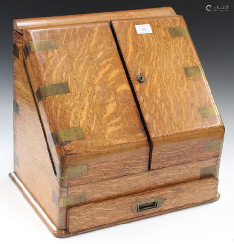 A Victorian oak and brass bound slope fronted stationery box, the double-hinged front enclosing