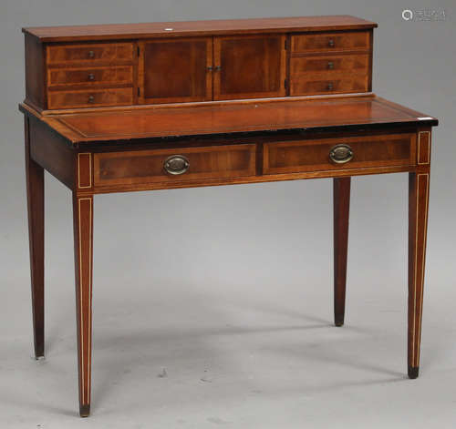 An early 20th century reproduction mahogany writing table, the gallery back fitted with two cupboard