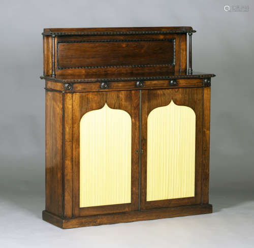 A Regency rosewood chiffonier, the shelf back above a pair of panel doors inset with fabric
